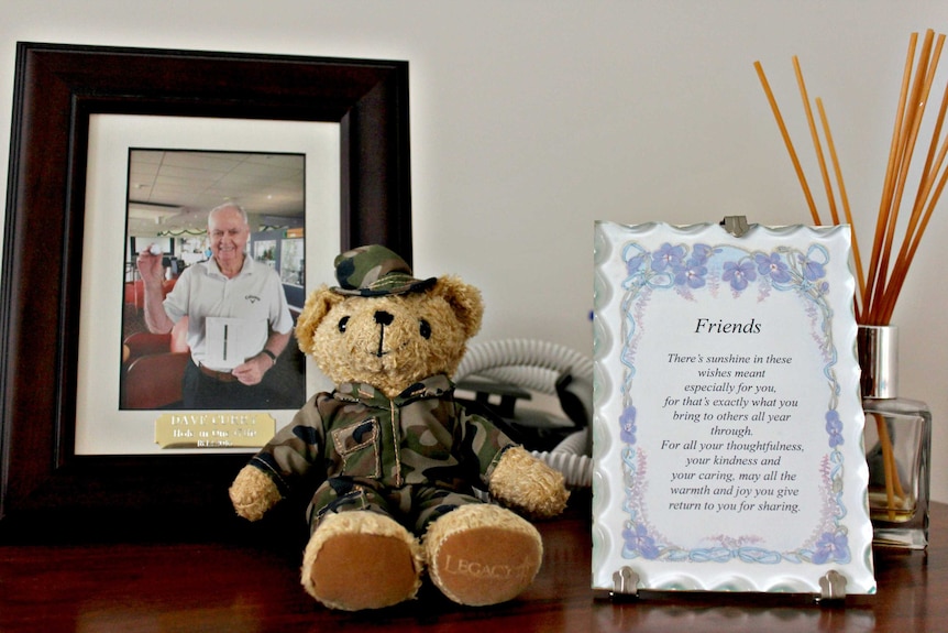 Mantelpiece in David Curry's home, photograph of hole-in-one golf ball and army dressed teddy bear.