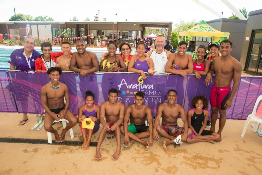 A team of swimmers beside a pool.