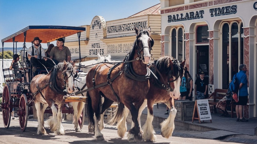 Before 1850s designed shop-fronts, horses pull a carriage in which a small group of people sit.