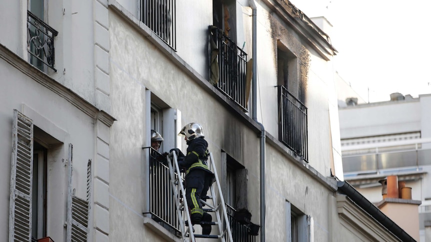 Firefighter climbs up ladder to apartment block after fire.