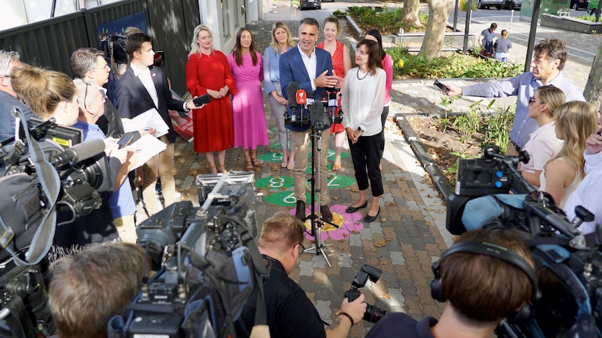 A man stands with women behind him