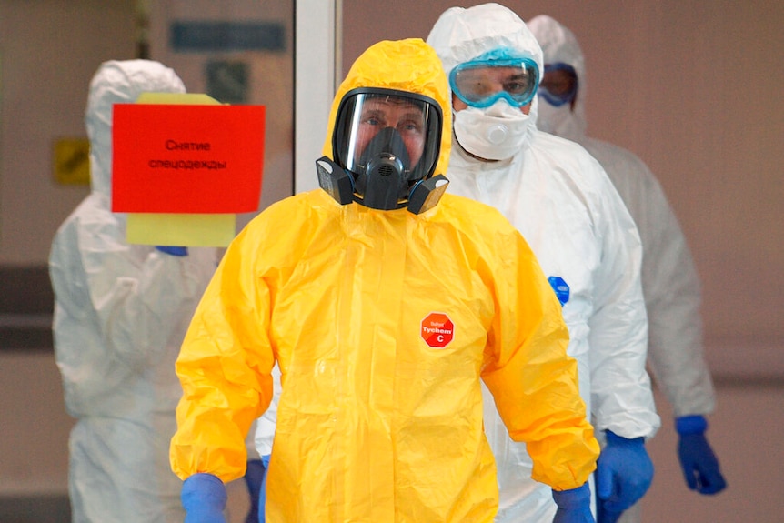 Vladimir Putin is pictured in a bright yellow hazmat suit and gas mask while he is followed by three others in white suits.