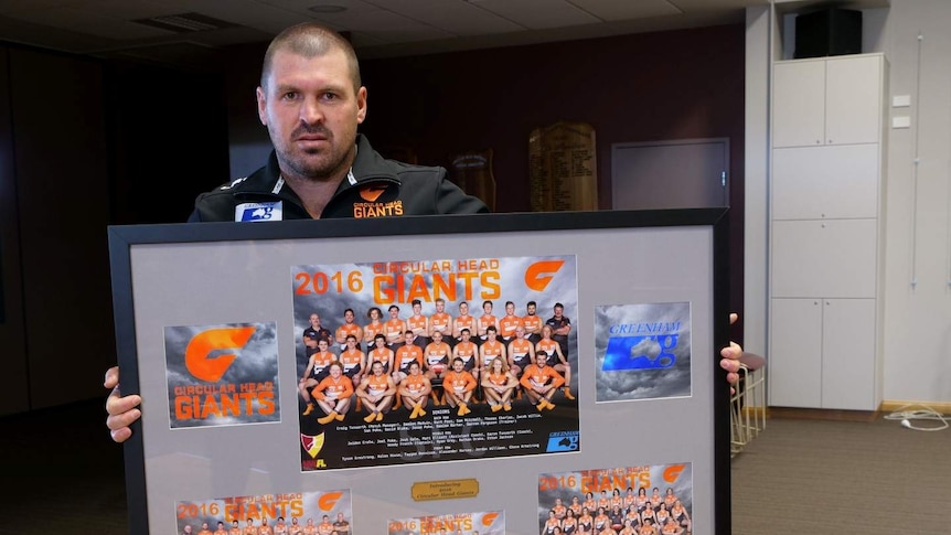 A man holds up a sports memorabilia poster