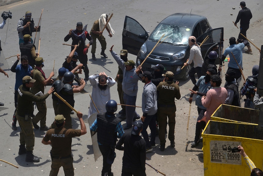 Geamurile mașinii sparte Un bărbat care poartă o cască și poartă bastoane amenință că îi bate pe protestatari