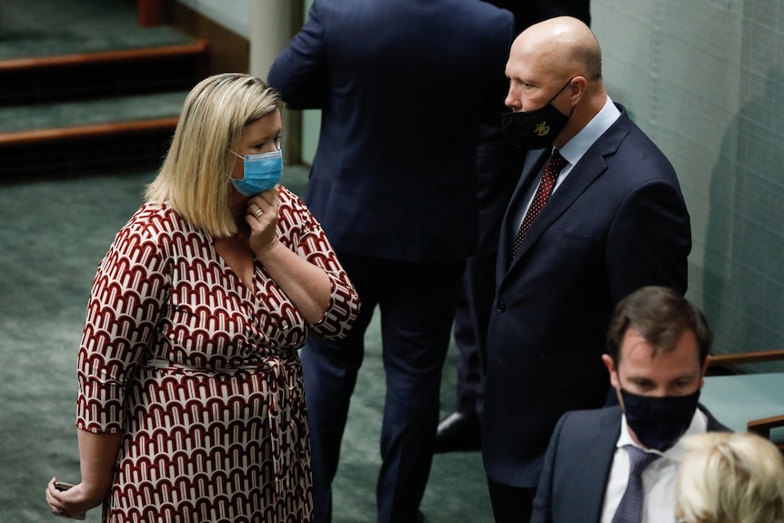 Bridget Archer holds a closed hand up to her throat as she speaks with Peter Dutton. 