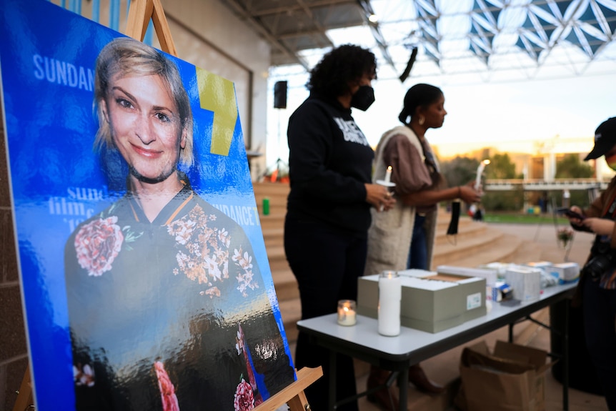 a picture of halyna hutchins smiling propped up on an easel at a vigil