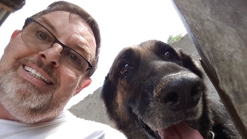 Jim Watkins smiles taking a selfie with a dog