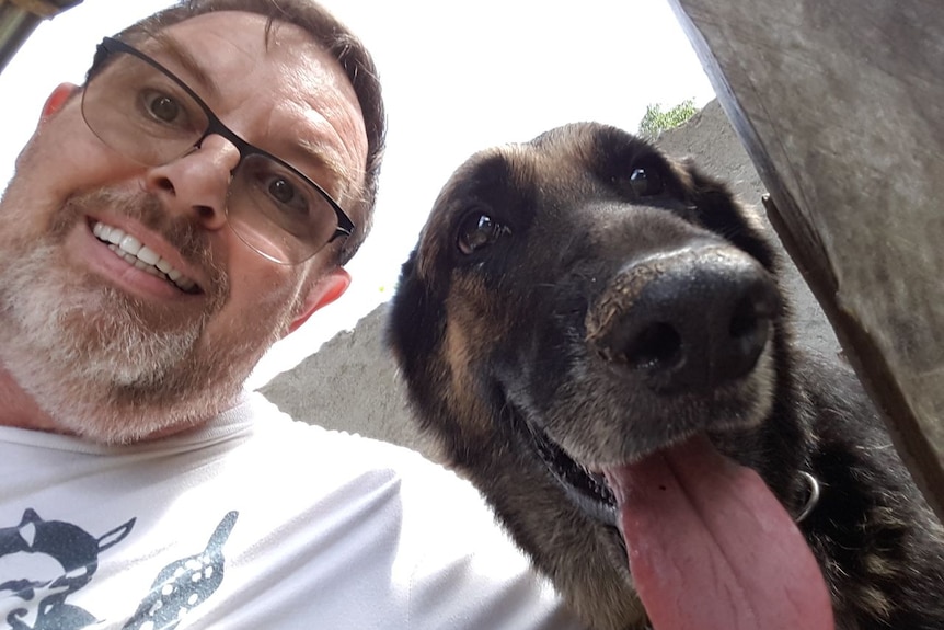 Jim Watkins smiles taking a selfie with a dog
