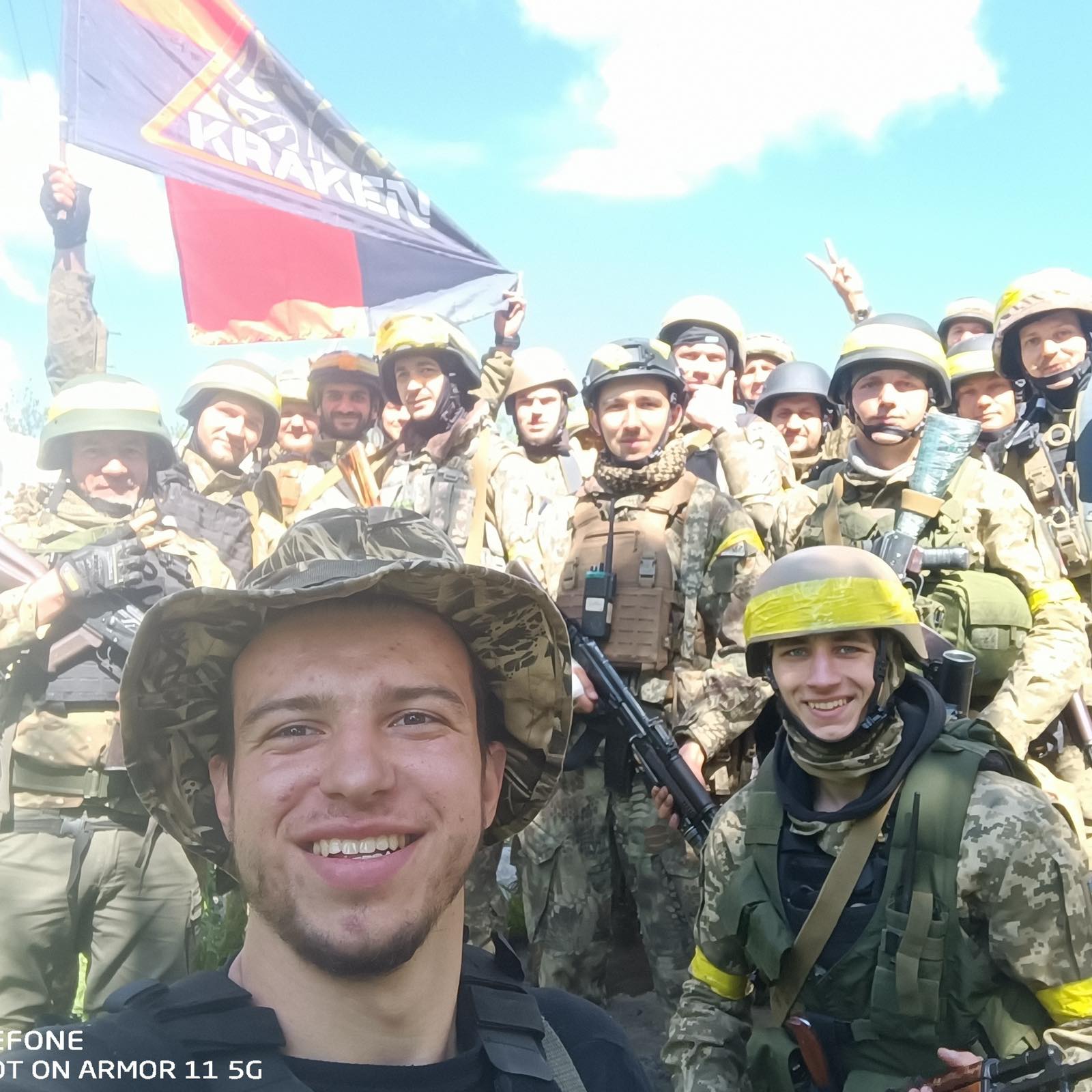 A selfie of a soldier smiling with a group of soldiers behind him. 