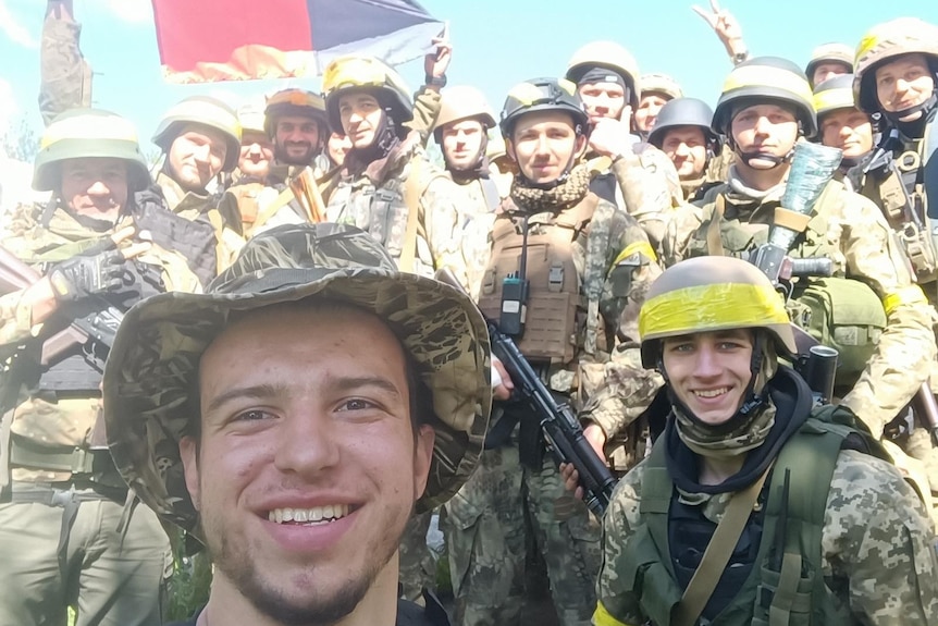A selfie of a soldier smiling with a group of soldiers behind him. 