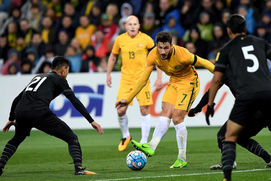 Mat Leckie tries to sneak a pass through two Thai defenders.