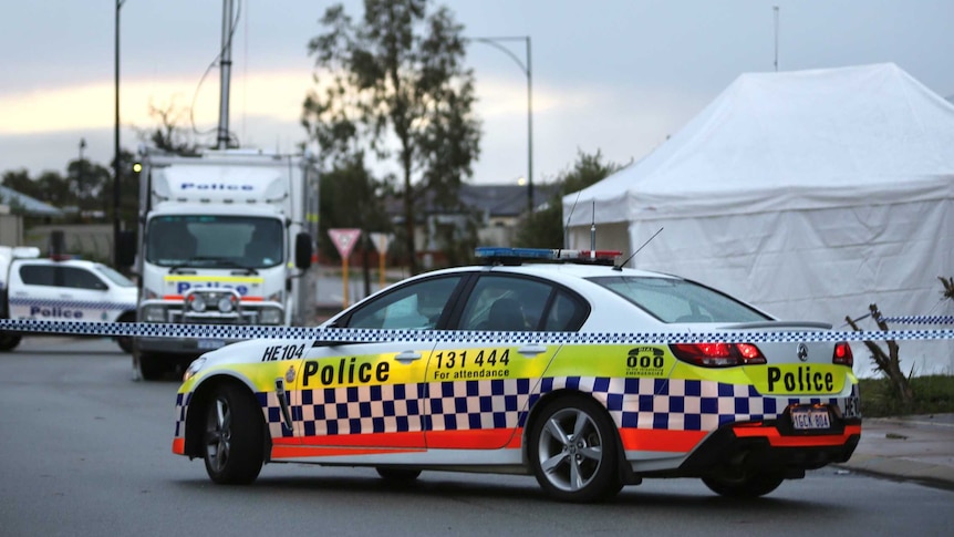 Police tape, police cars and a forensic tent on a suburban street in the early morning.