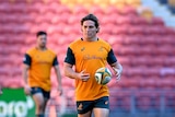 An Australian Wallabies player juggles a ball between his hands as he walks on the field during training.