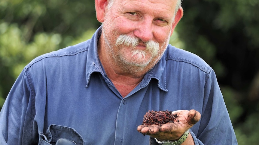 A man holds worms in his hands