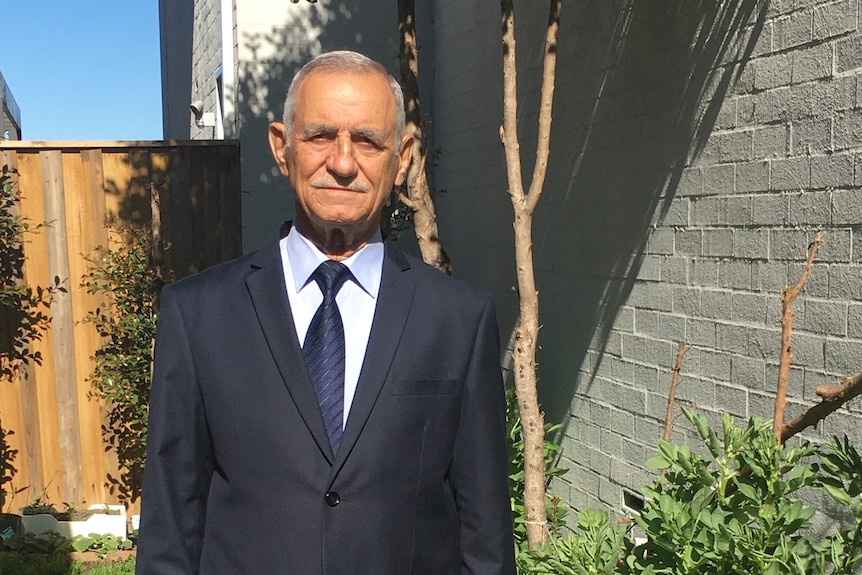 An Iraqi man in a suit standing in a garden.