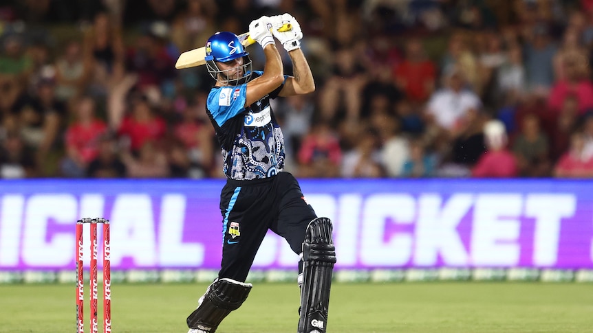 An Adelaide Strikers batsman stands just out of his crease with arms extended having hit the ball down the ground.