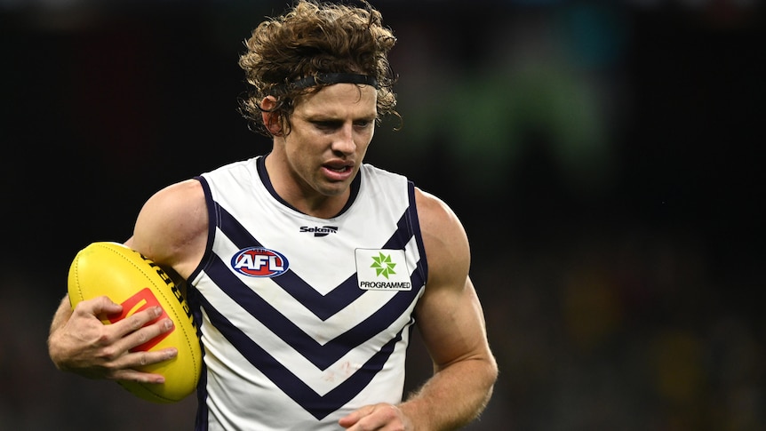Nat Fyfe holds the ball and looks towards the ground