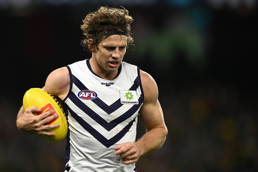Nat Fyfe holds the ball and looks towards the ground
