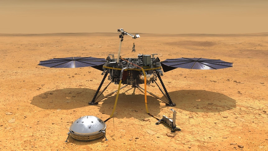 A spacecraft with instruments and solar panels sitting on the surface of a red dusty planet