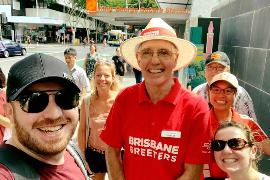 A man in a red shirt with a group of tourists.