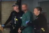 An image of the shooter being escorted from hospital.