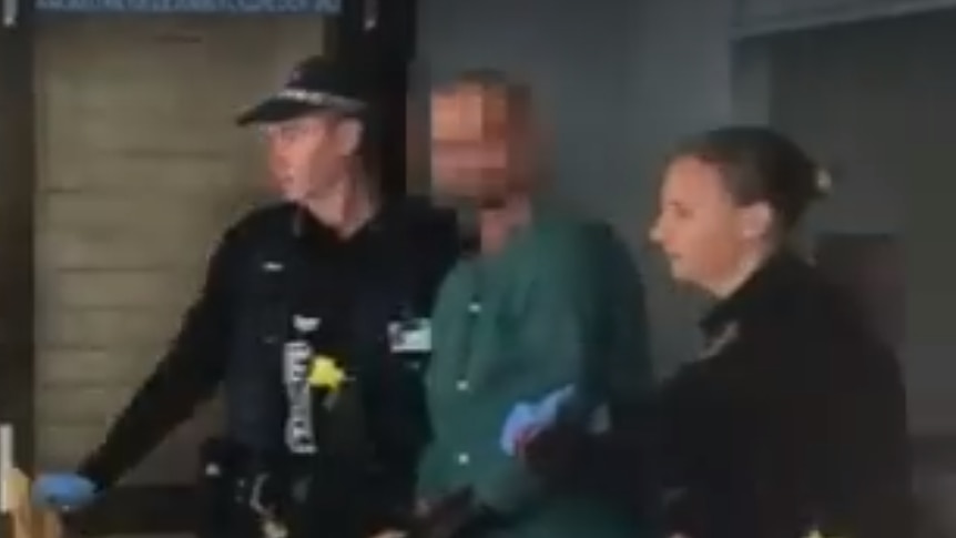 An image of the shooter being escorted from hospital.