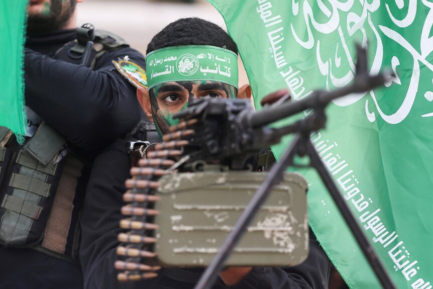 A young Hamas militant holding up a machine gun. 