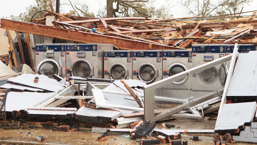 A row of washing machine stand in the middle of a collapsed building.