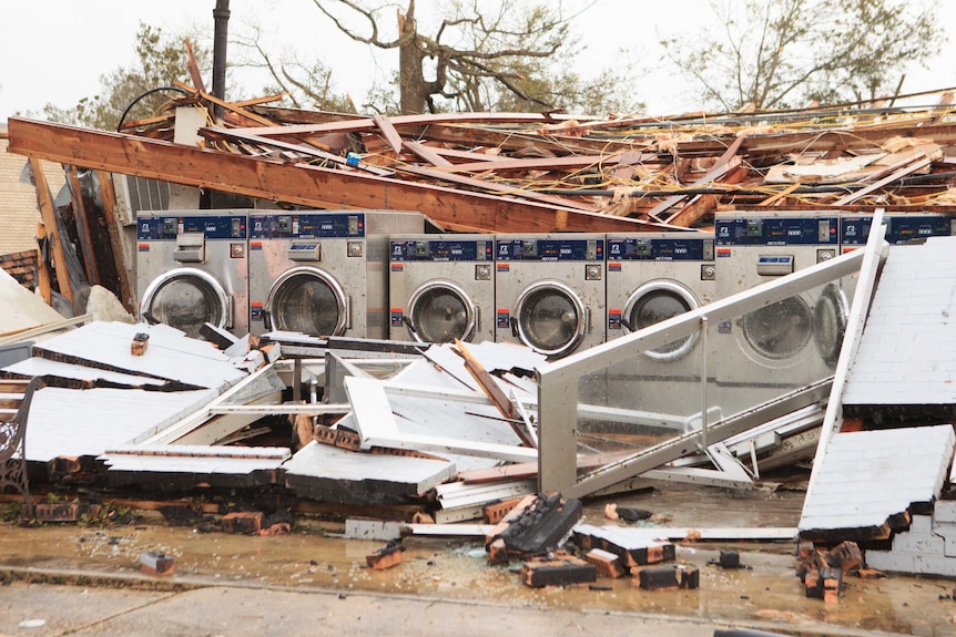 A row of washing machine stand in the middle of a collapsed building.
