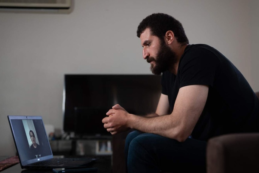 A man talks to a woman on a laptop