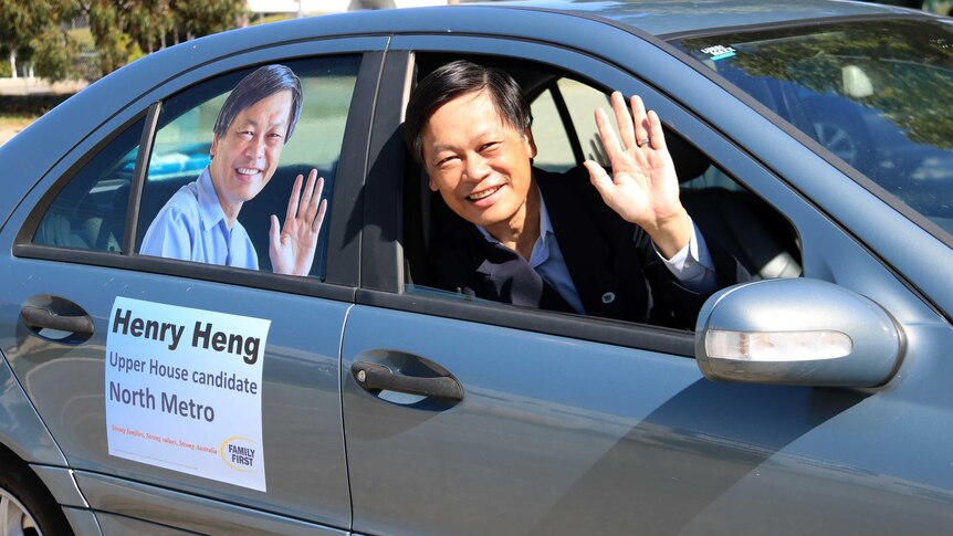 Henry Heng in his car covered in election campaign material
