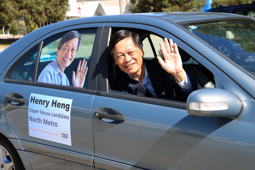 Henry Heng in his car covered in election campaign material