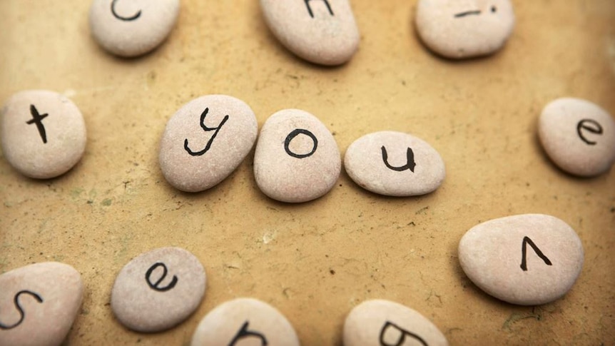 Pebbles with letters, three spell out the word 'you'