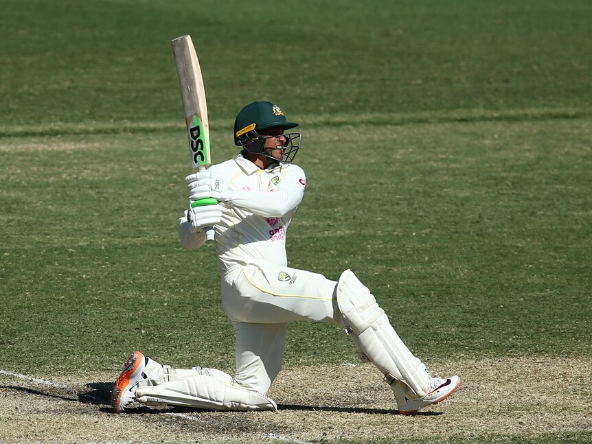 Australian batsman Usman Khawaja goes down on one knee to hit the ball through the leg side.