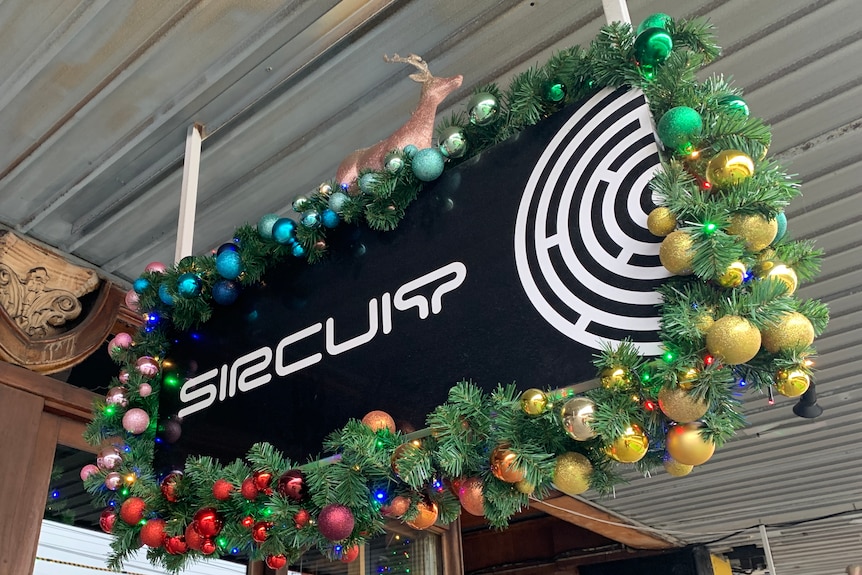 Festive Christmas decorations adorn a sign reading 'sircuit' outside a bar.