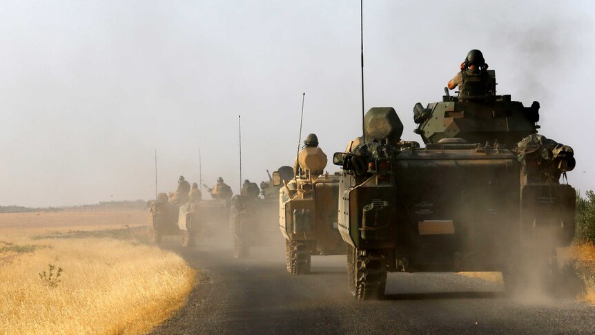 Turkish armoured personnel carriers drive towards the border.