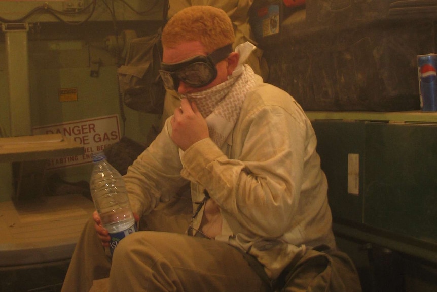 A man with goggles on wraps a scarf around his mouth.