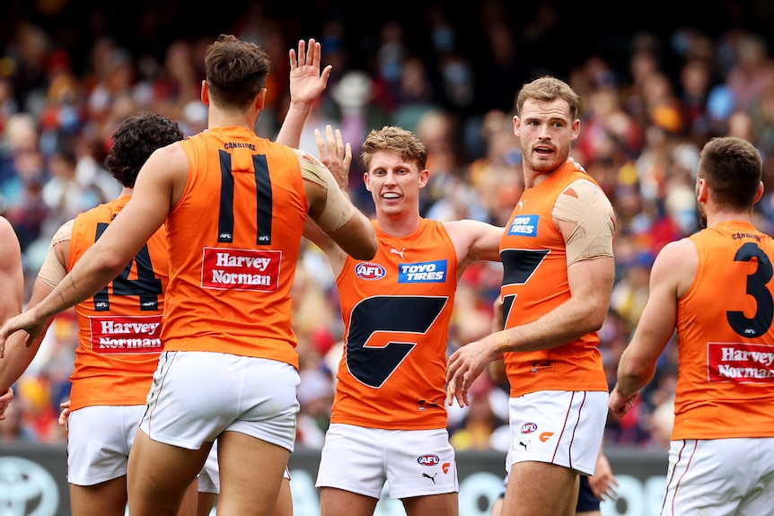 GWS players stand around and high five Lachie Whitfield