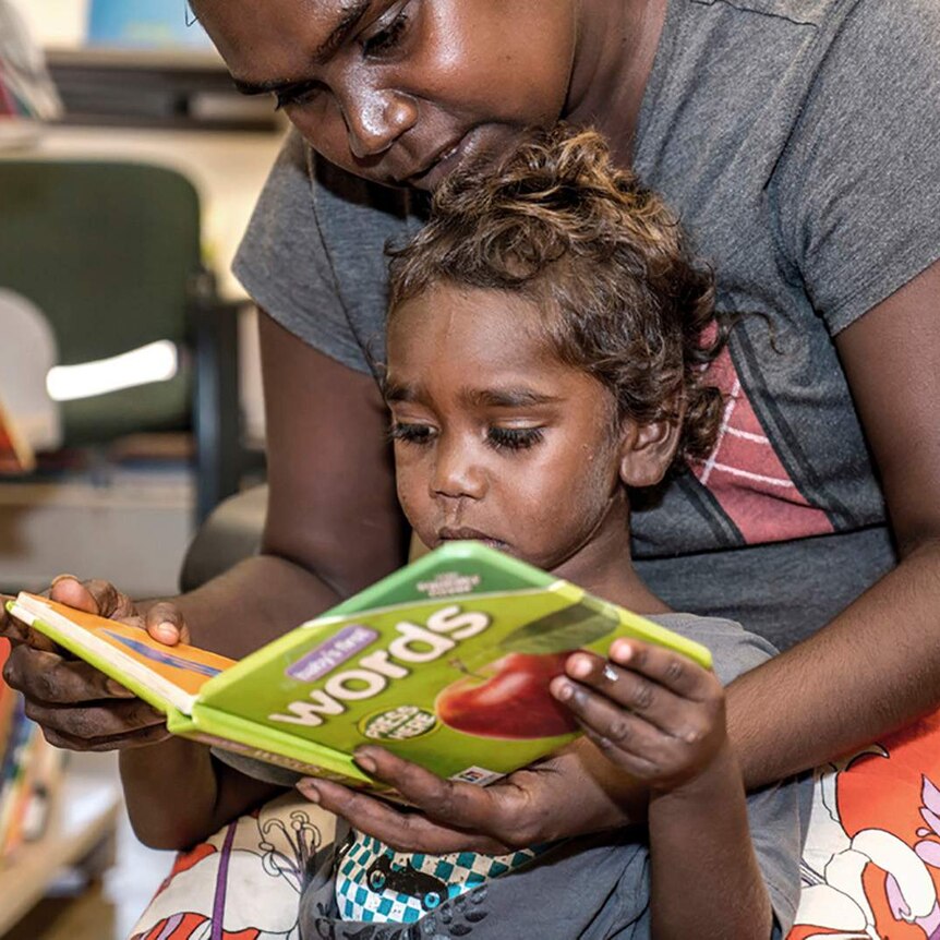 A photo of a mother reading a book to herchild.