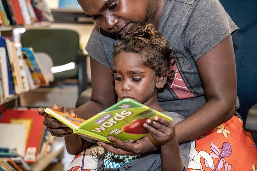 A photo of a mother reading a book to herchild.