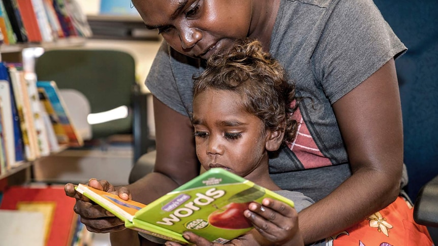 A photo of a mother reading a book to herchild.