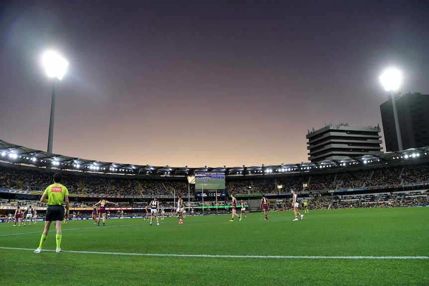 A general view of the Gabba hosting an AFL match with two light towers in operation.