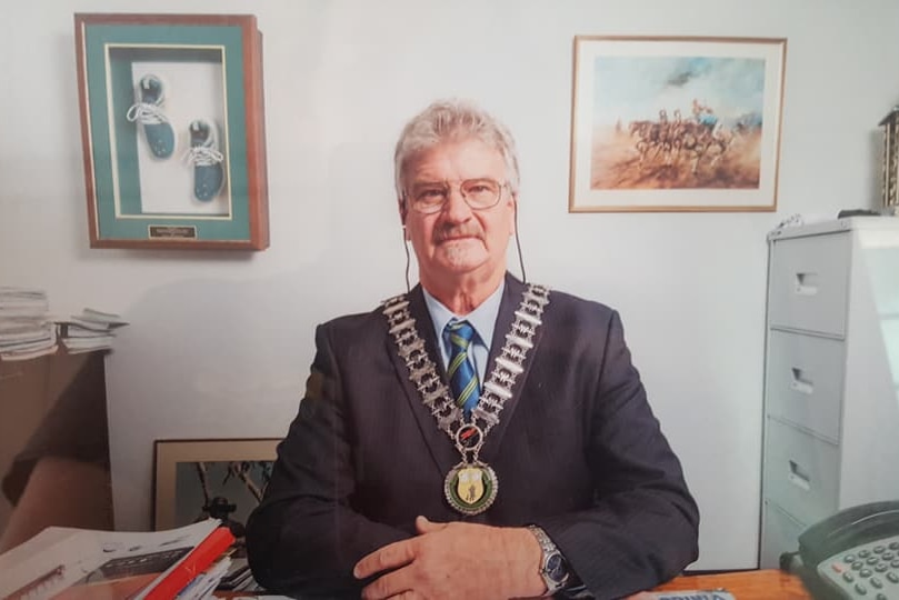 'Butch' Lenton sitting at his desk, dressed in his mayoral chain. Looking at the camera.