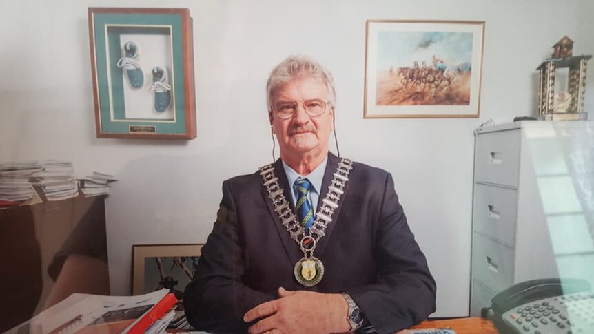 'Butch' Lenton sitting at his desk, dressed in his mayoral chain. Looking at the camera.