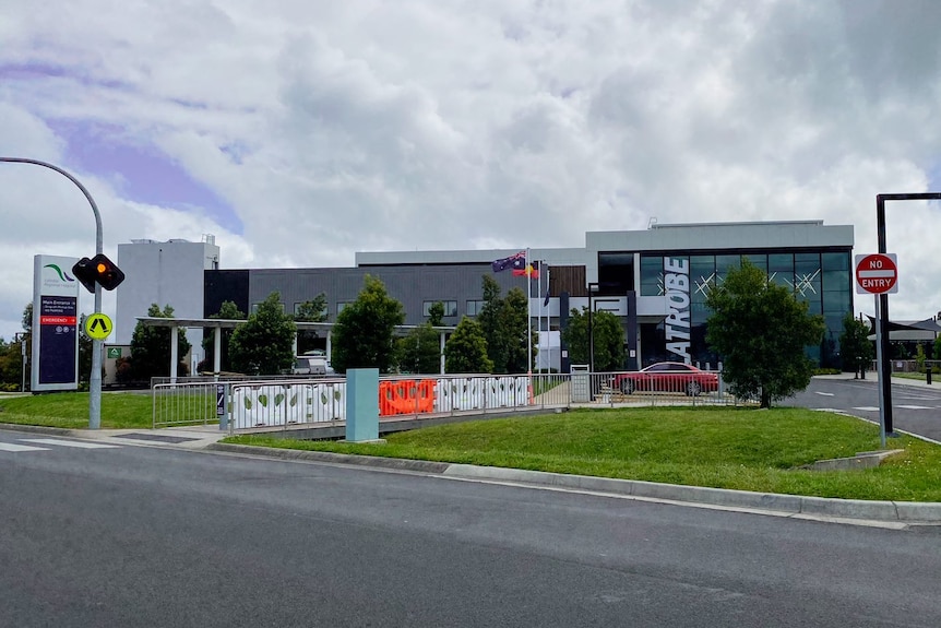 A large grey hospital with temporary fencing out the front