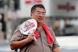 A man uses a fan as he walks on a street in Tokyo.