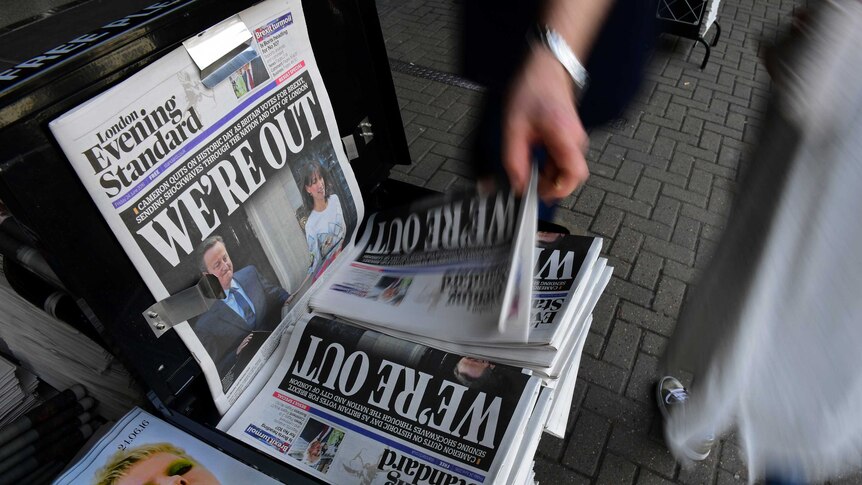 A man takes a copy of the London Evening Standard newspaper reporting the Brexit Leave vote and David Cameron's resignation