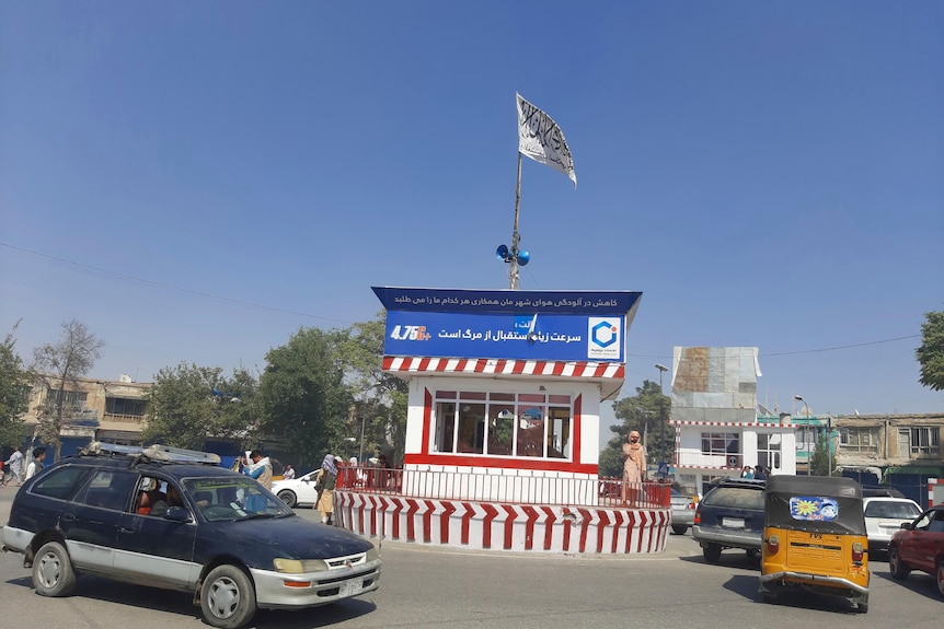 The Taliban's white flag flutters above Kunduz city's main square as traffic moves past