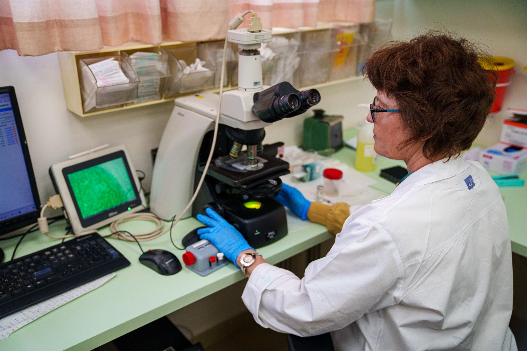 A scientist holds a machine as she looks at a screen displaying sperm samples.