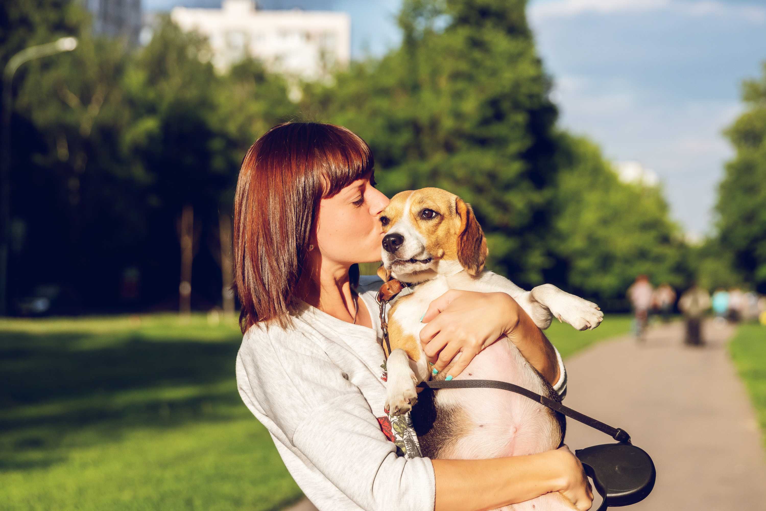 Woman hugging and kissing her dog in the park for a story about choosing not to have children.